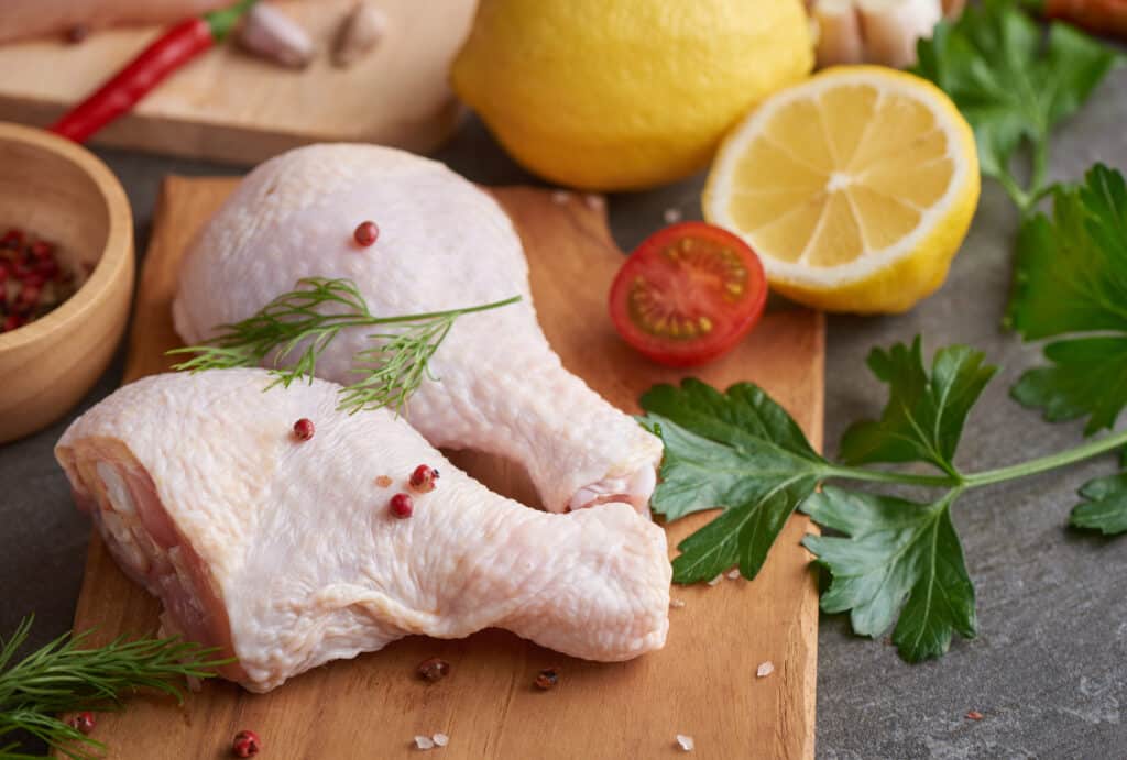 fresh chicken meat portions cooking barbecuing with fresh seasoning raw uncooked chicken leg cutting board